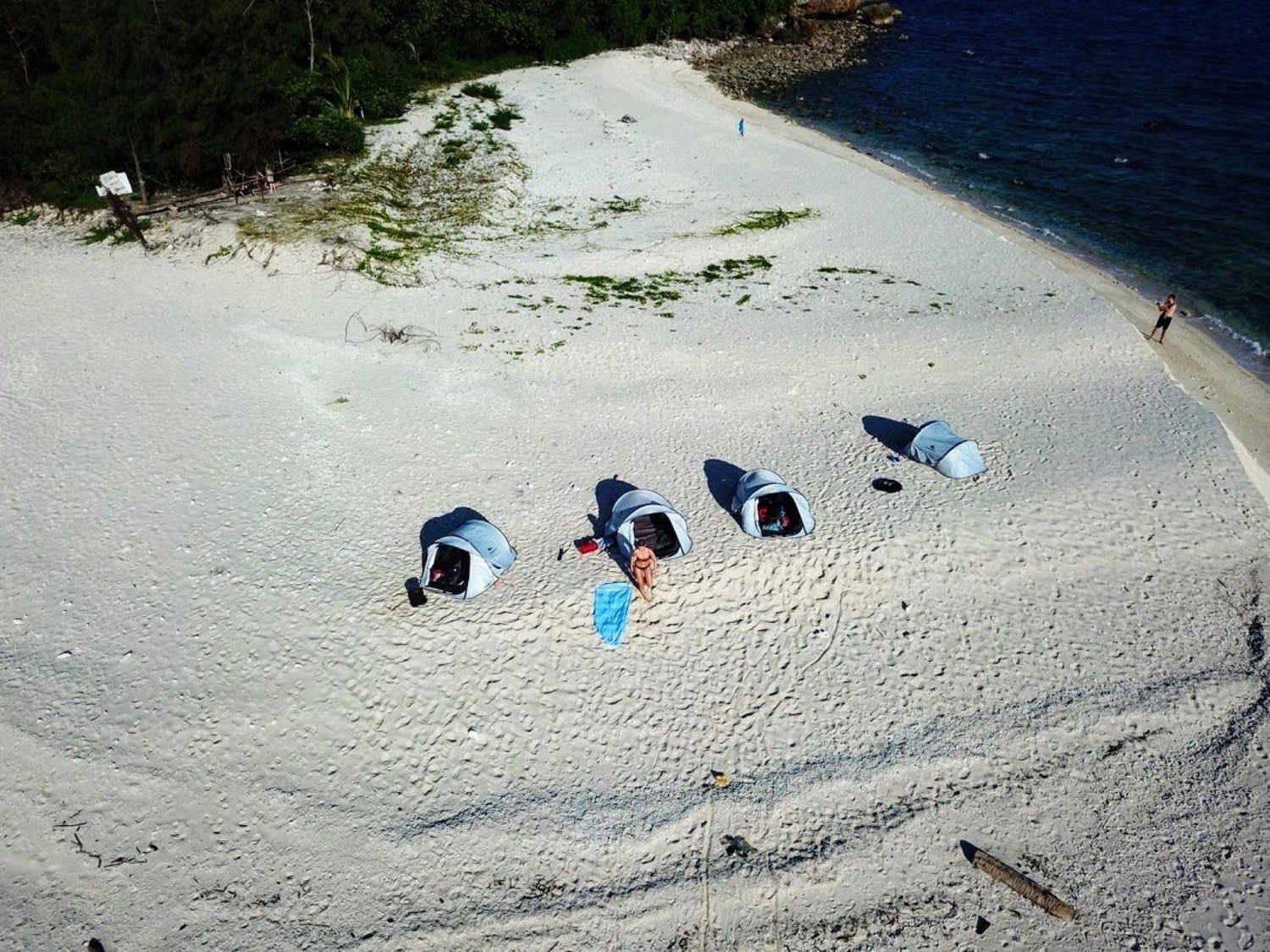 Aerial view of camping tents lined up on the white coral sand of Koh Kye